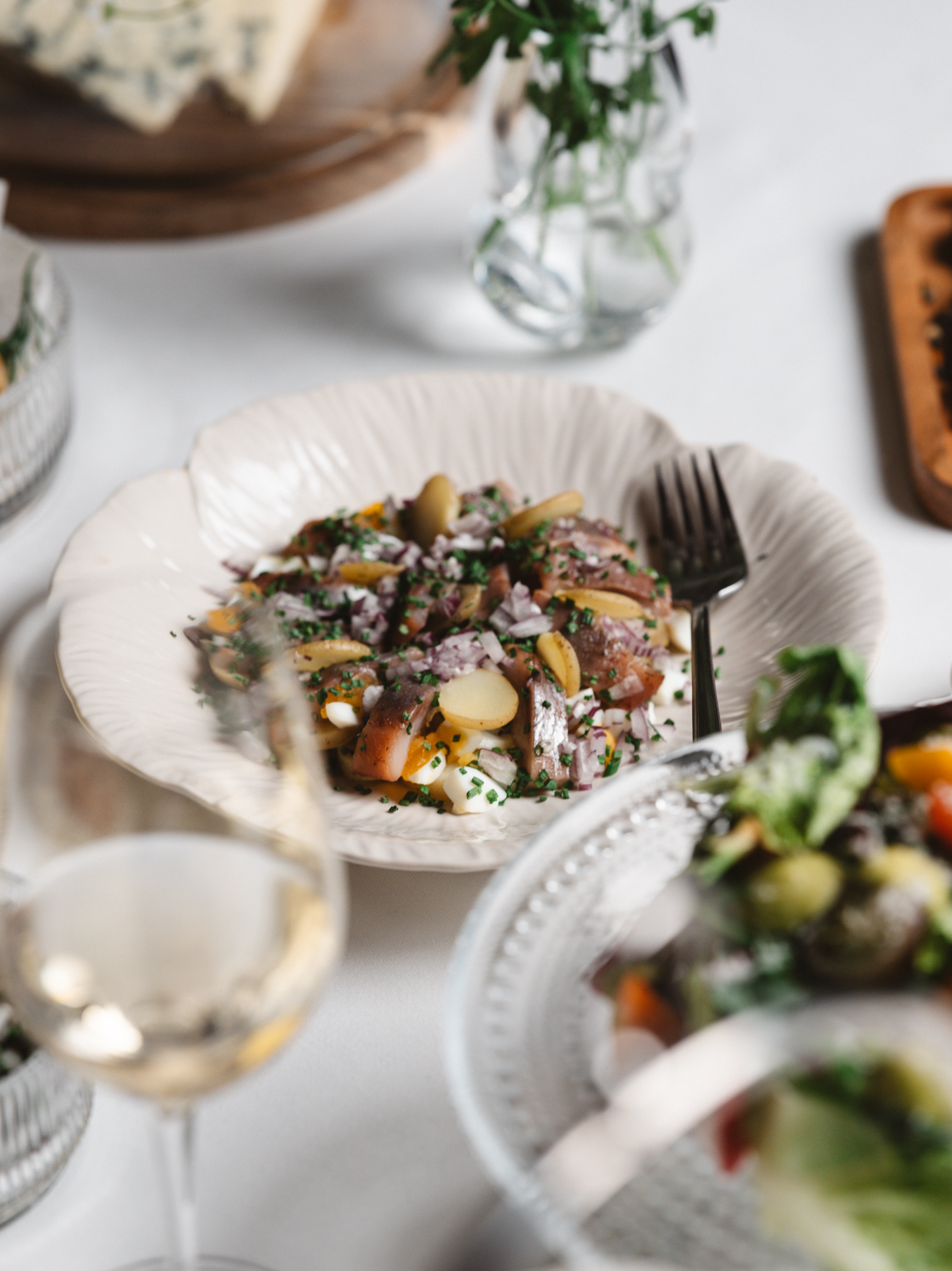 Elegant dish with meat and vegetables in a decorative bowl, served with red wine on a wooden table