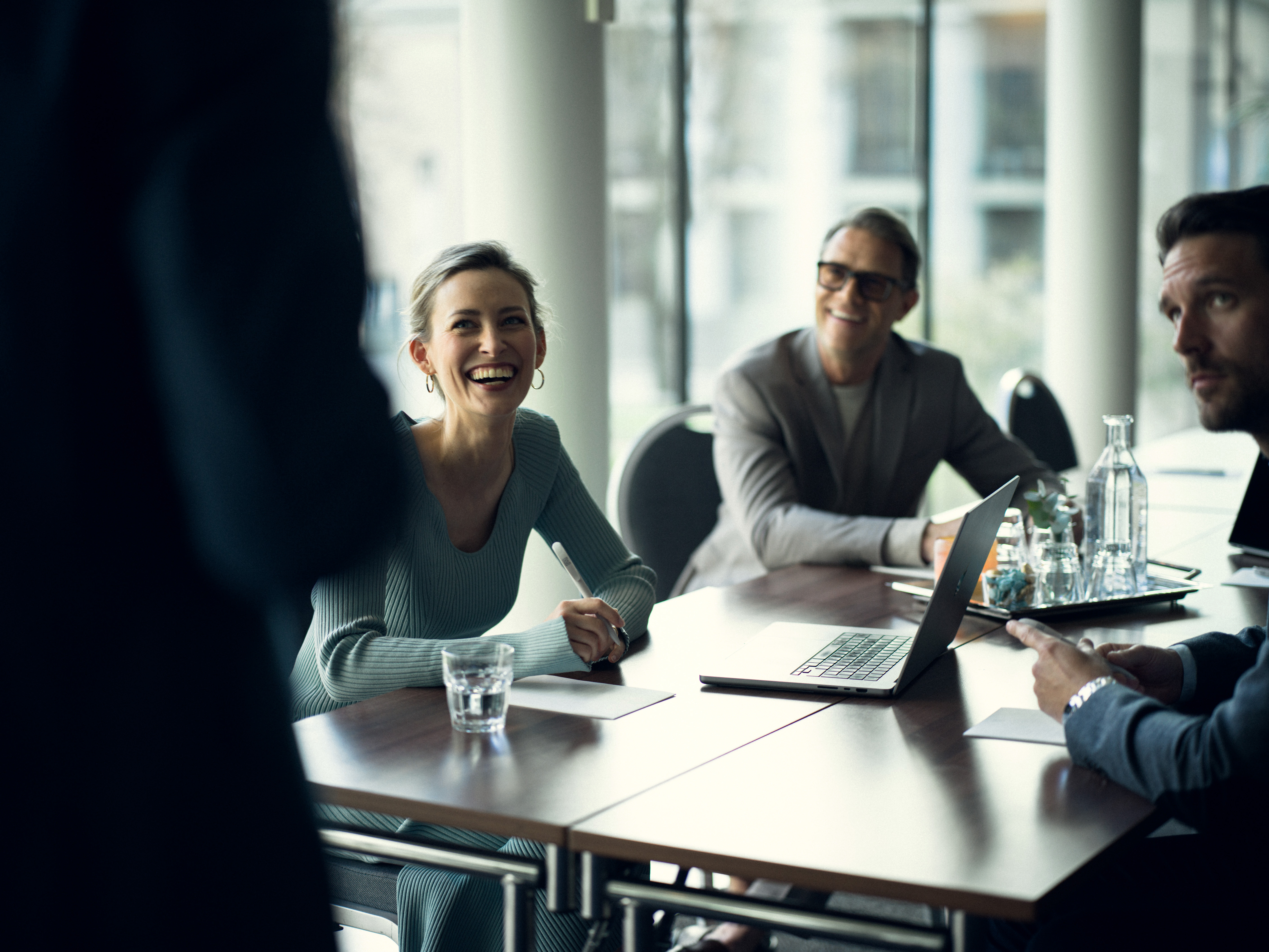 People leaning over conference table with pens in hands