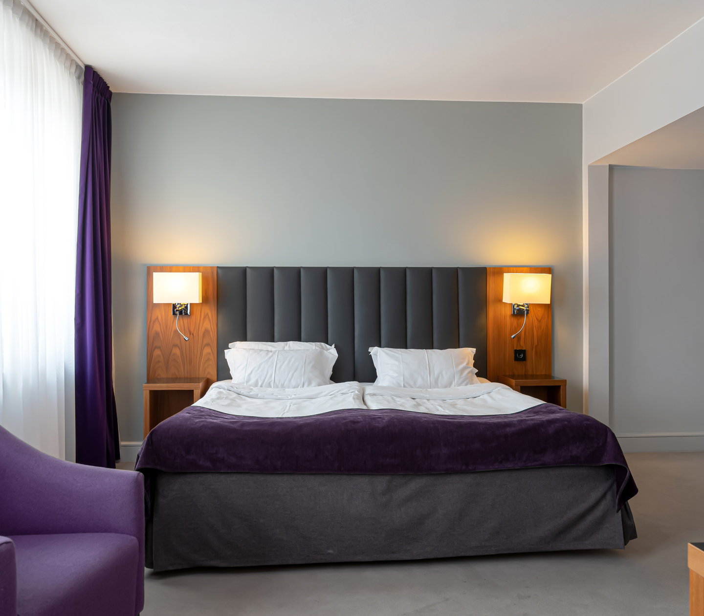 Hotel room with double bed, armchair and bedside lamps