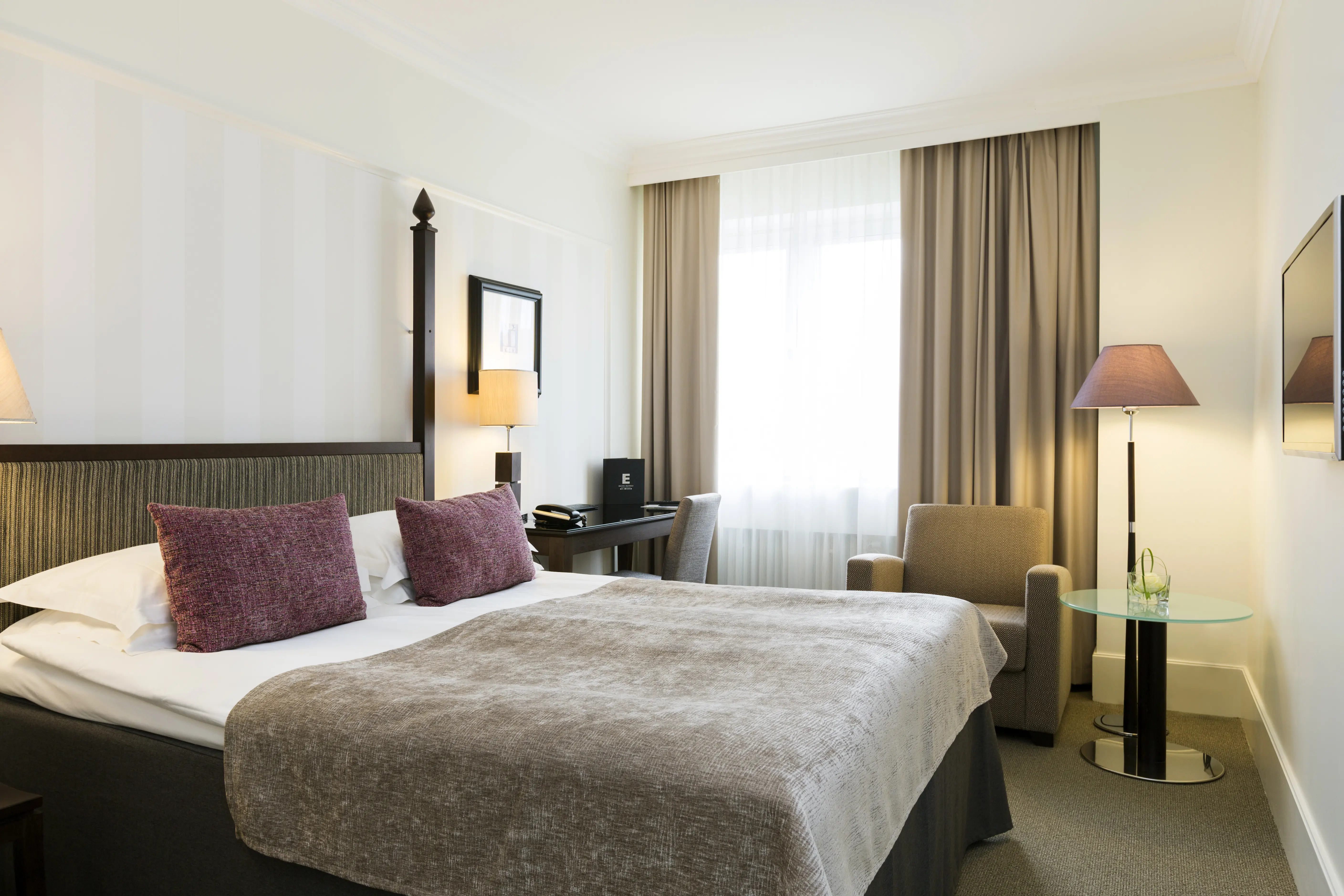 Cozy hotel room with double bed, desk and armchair