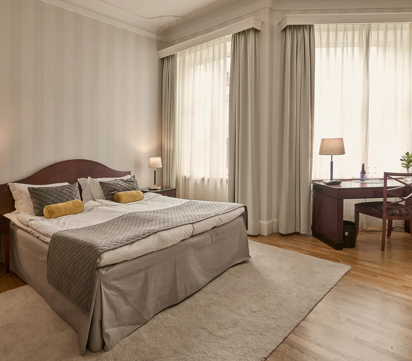 Suite with double bed, seating area and green tiled stove