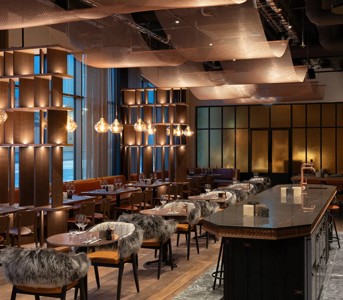 Wide view of Restaurant Fe featuring multiple seating areas with blankets and copper sails suspended from the ceiling.