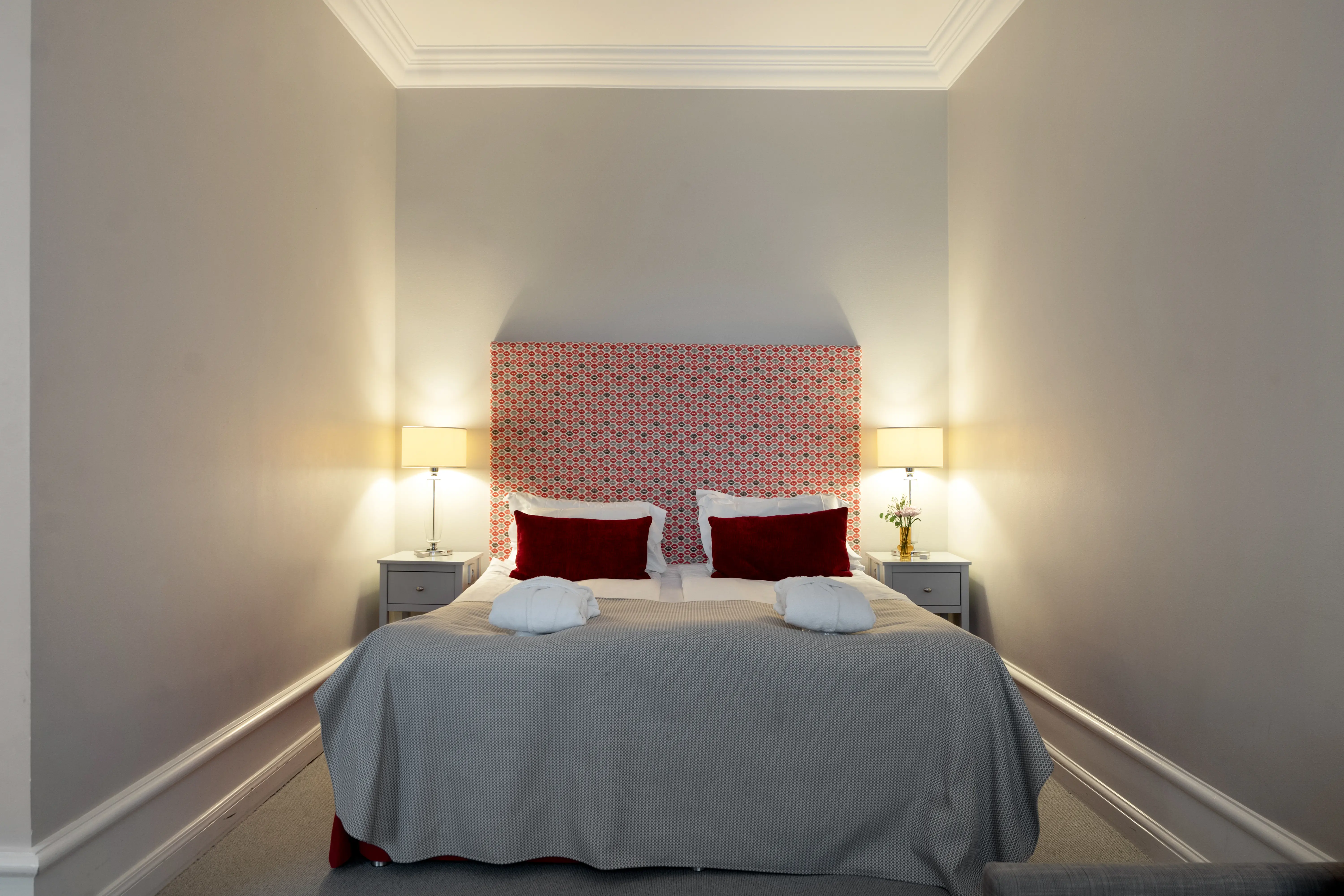 Hotel room with double bed, red headboard and bedside lamps