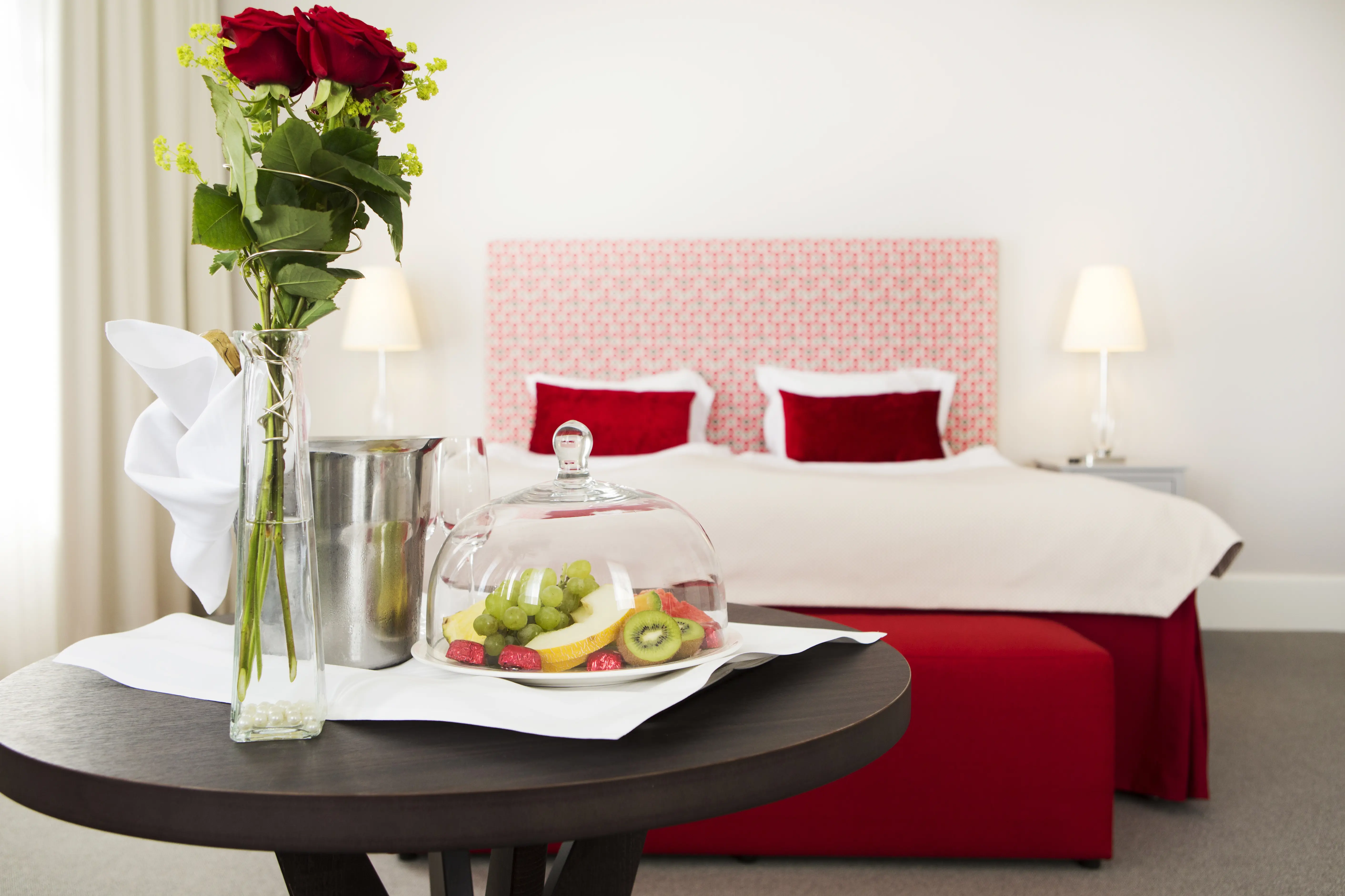 Bright suite with double bed, red textiles and vip on table in front
