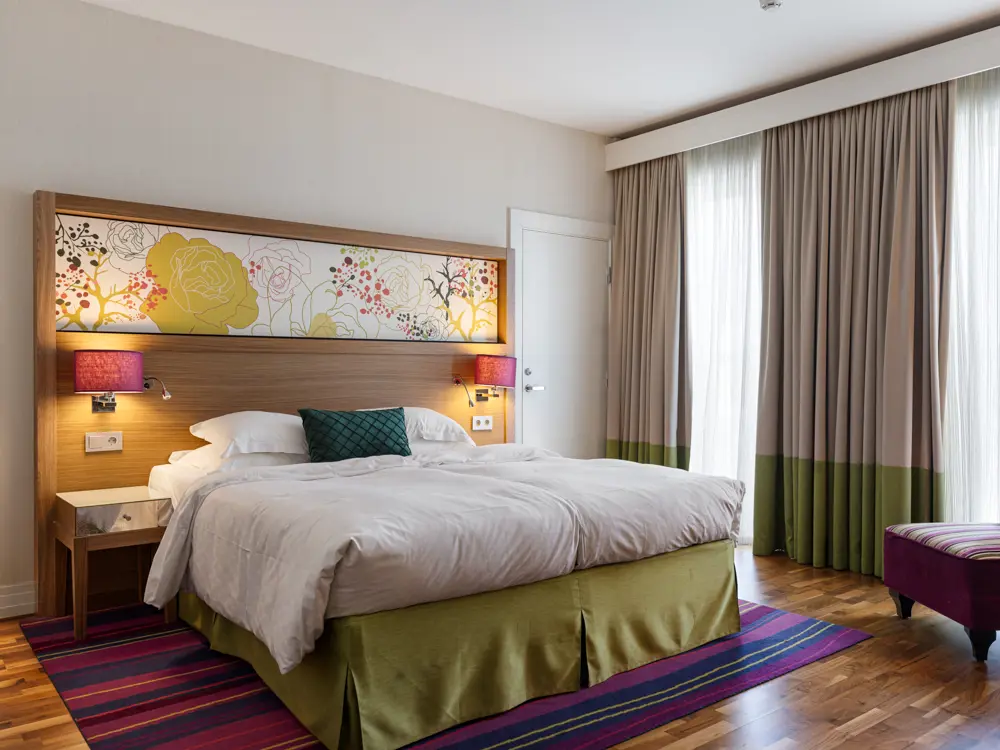 Large hotel room with double bed, armchair and window