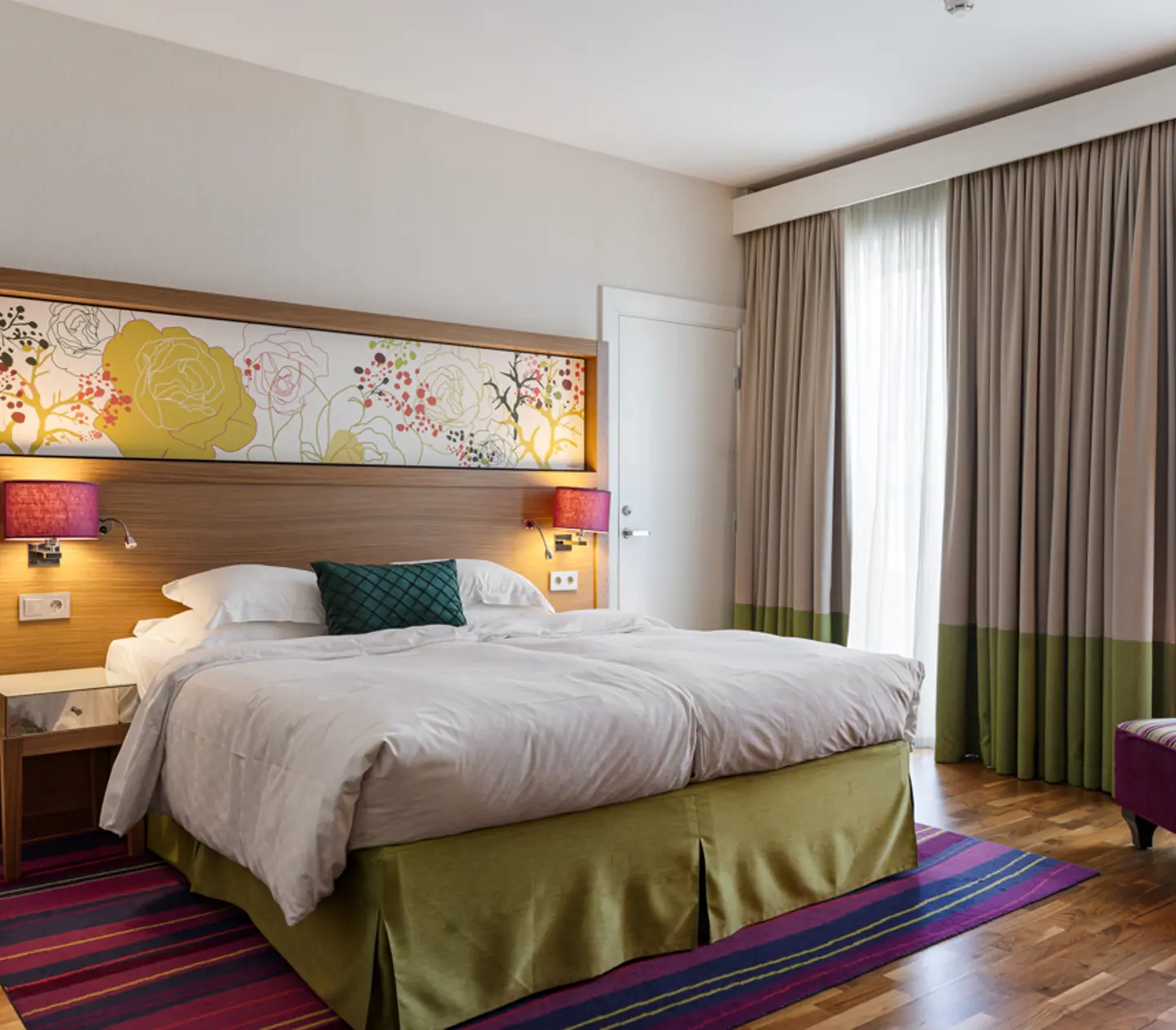 Large hotel room with double bed, armchair and window