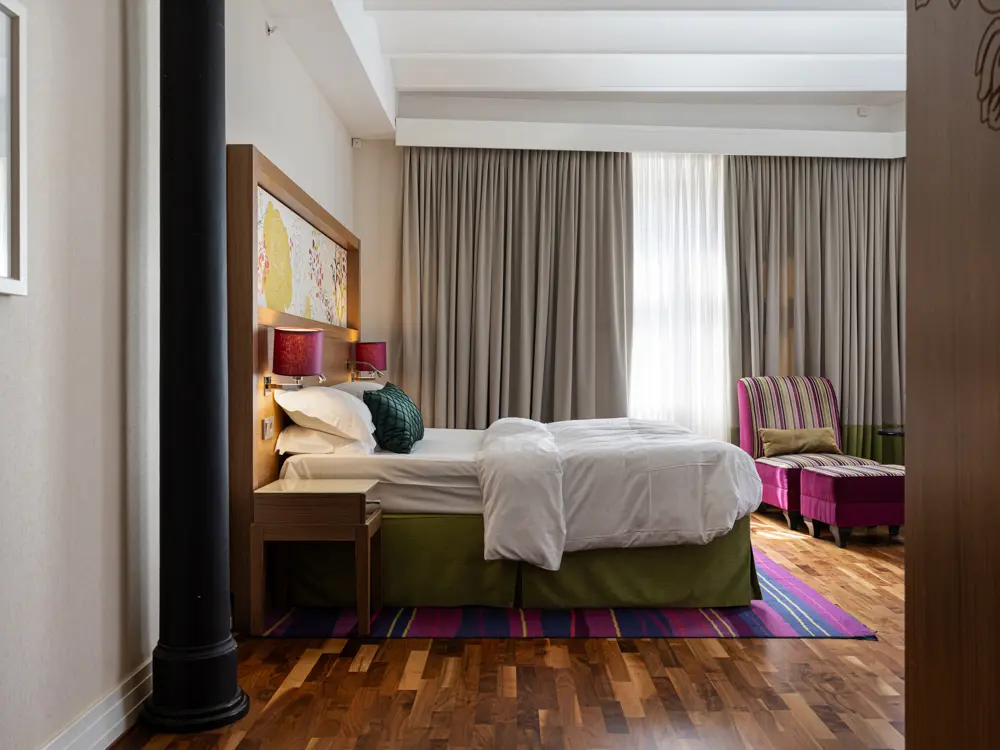 Hotel room with double bed, armchair and large windows