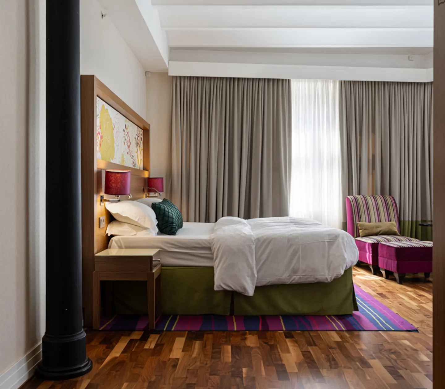 Hotel room with double bed, armchair and large windows