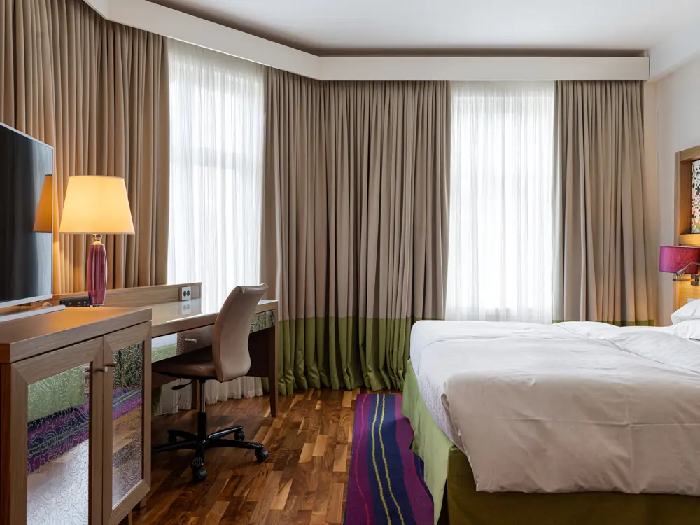 Hotel room with double bed, armchairs and desk