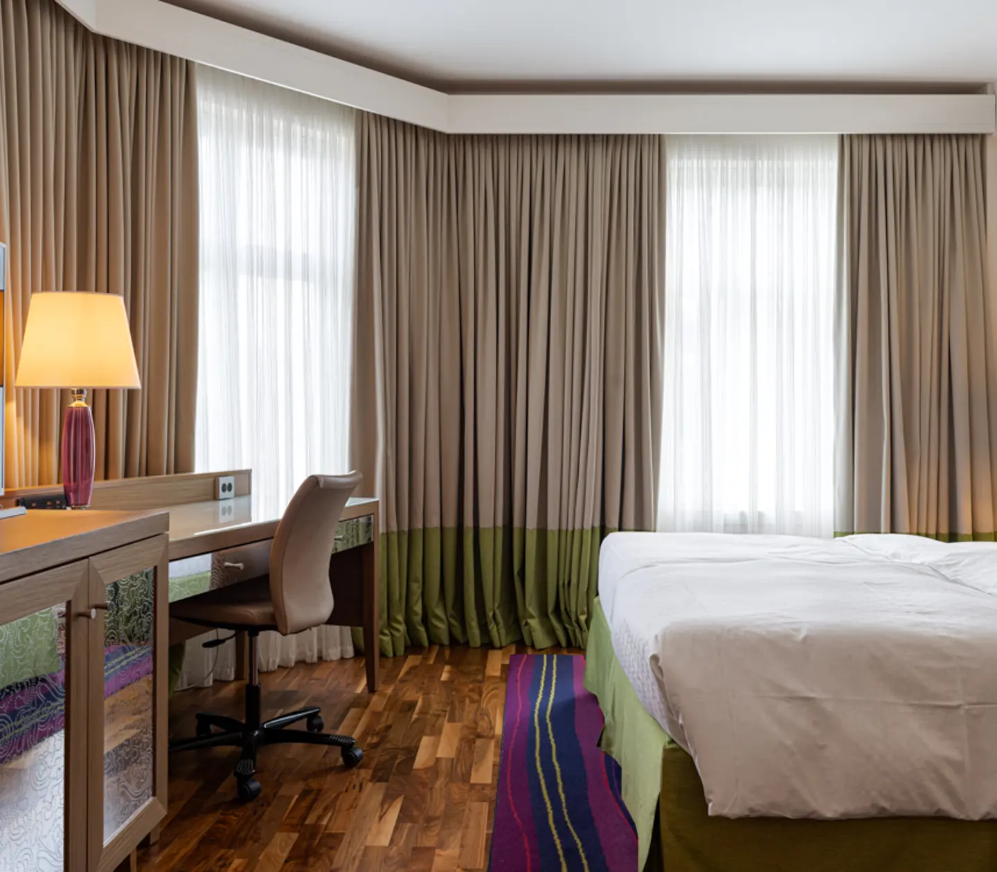 Hotel room with double bed, armchairs and desk