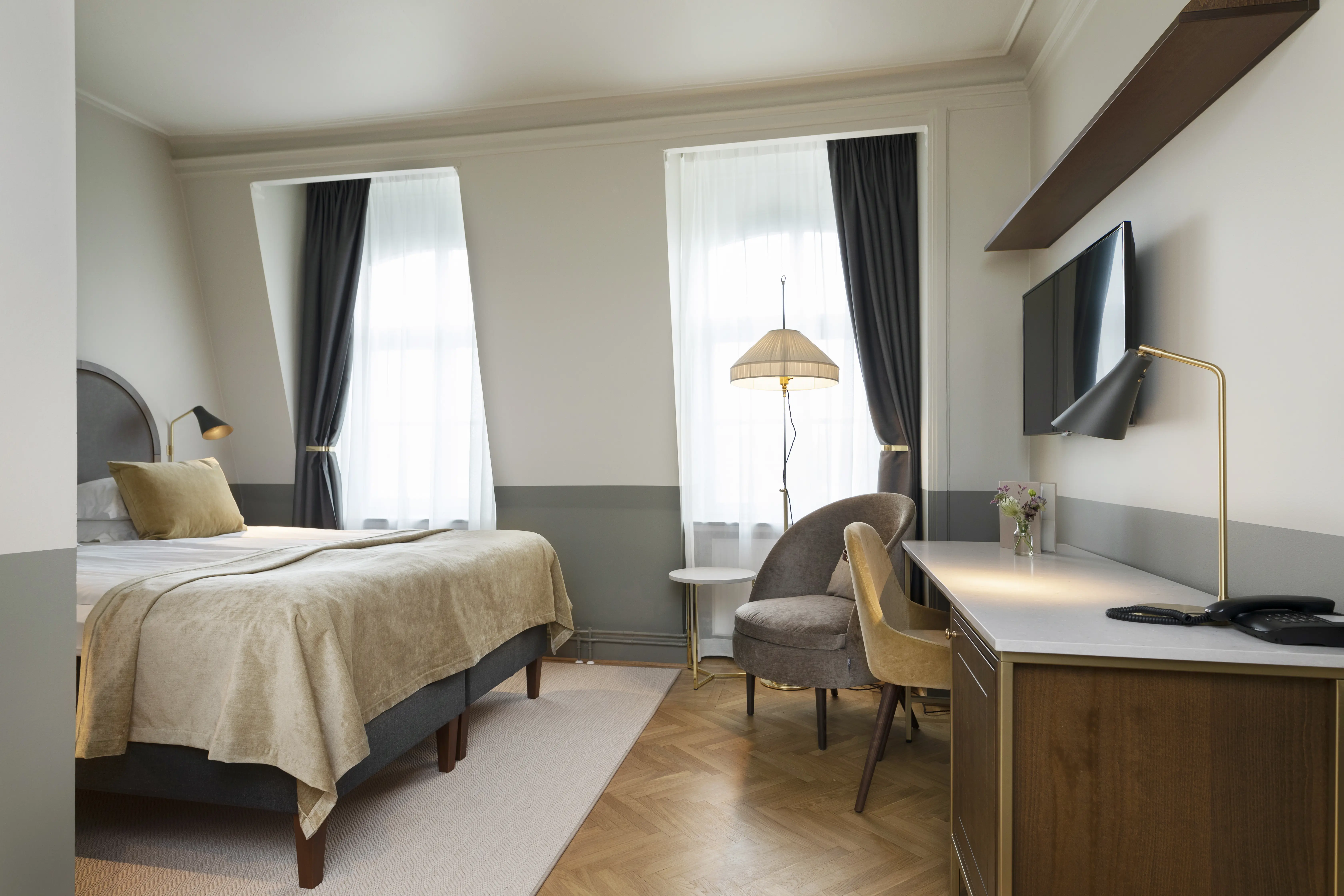 Bright hotel room with double bed, desk, armchair and window