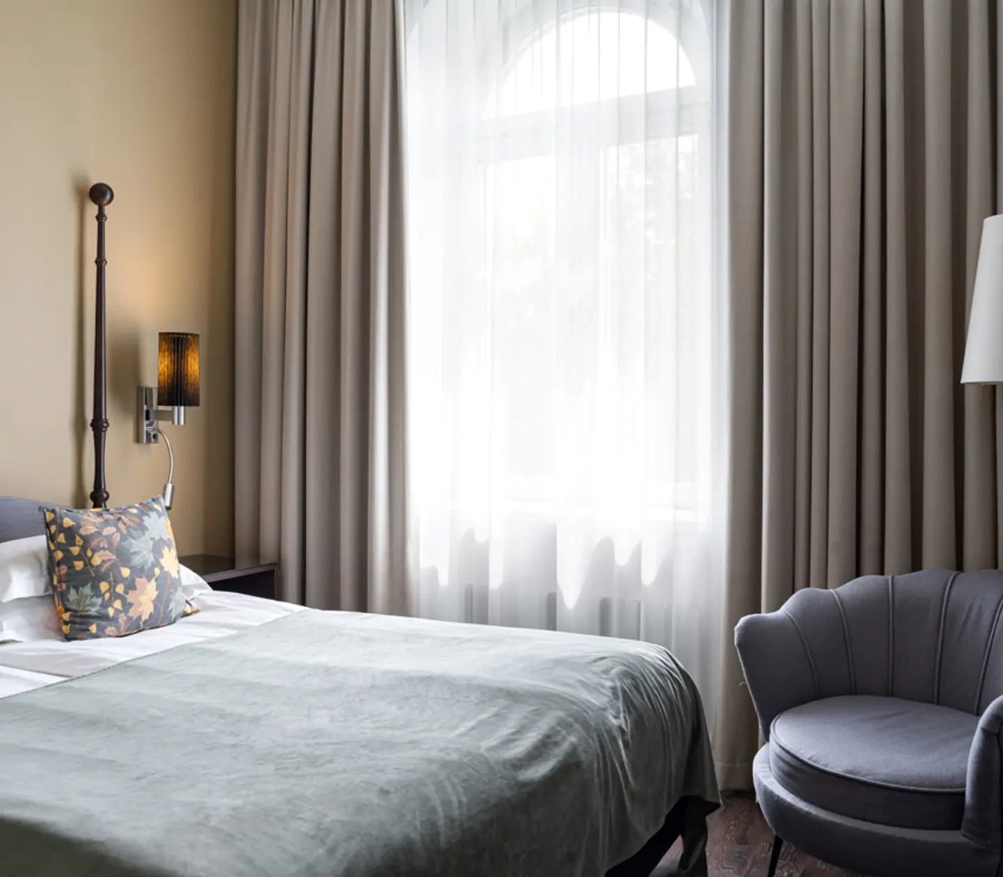 Ljust hotellrum med säng, fåtölj och fönster