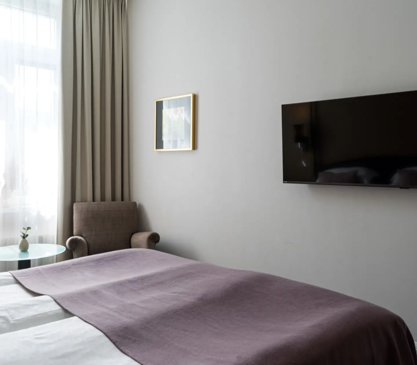 Ljust hotellrum med skrivbord, spegel och säng