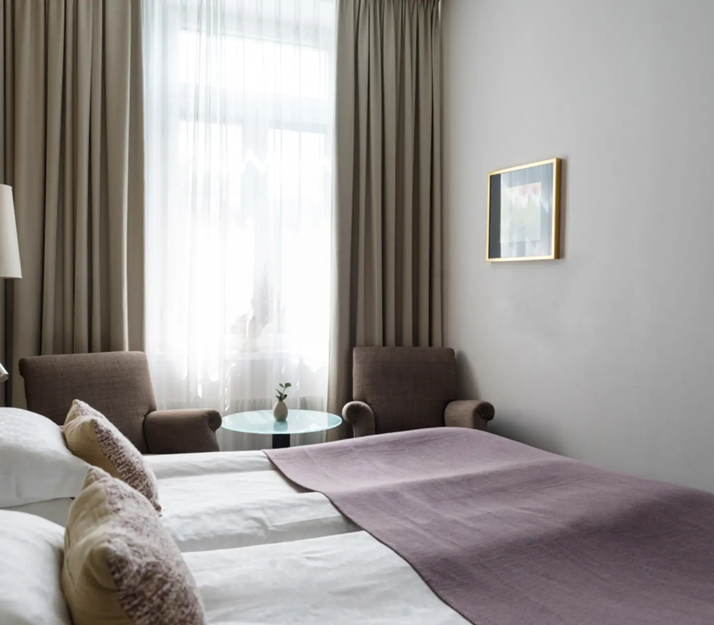 Ljust hotellrum med säng, skrivbord och fönster