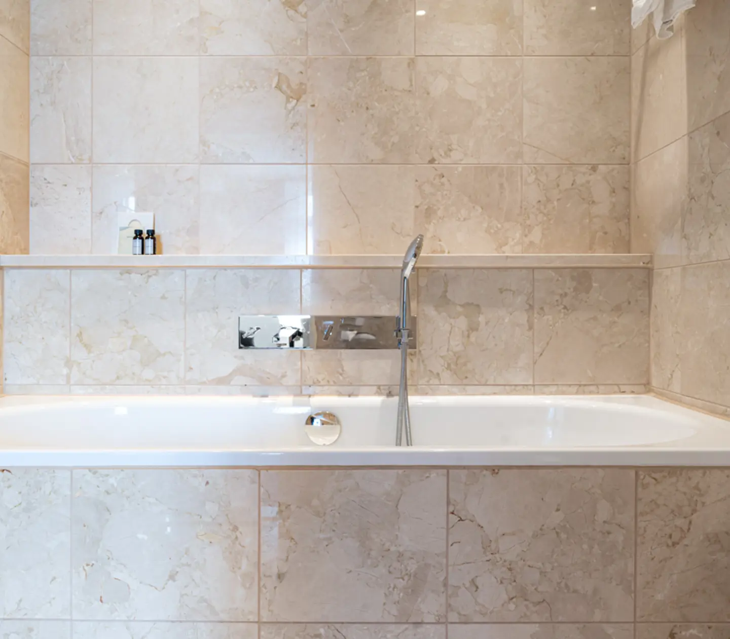 Beige badrum med dusch, badkar och handdukar