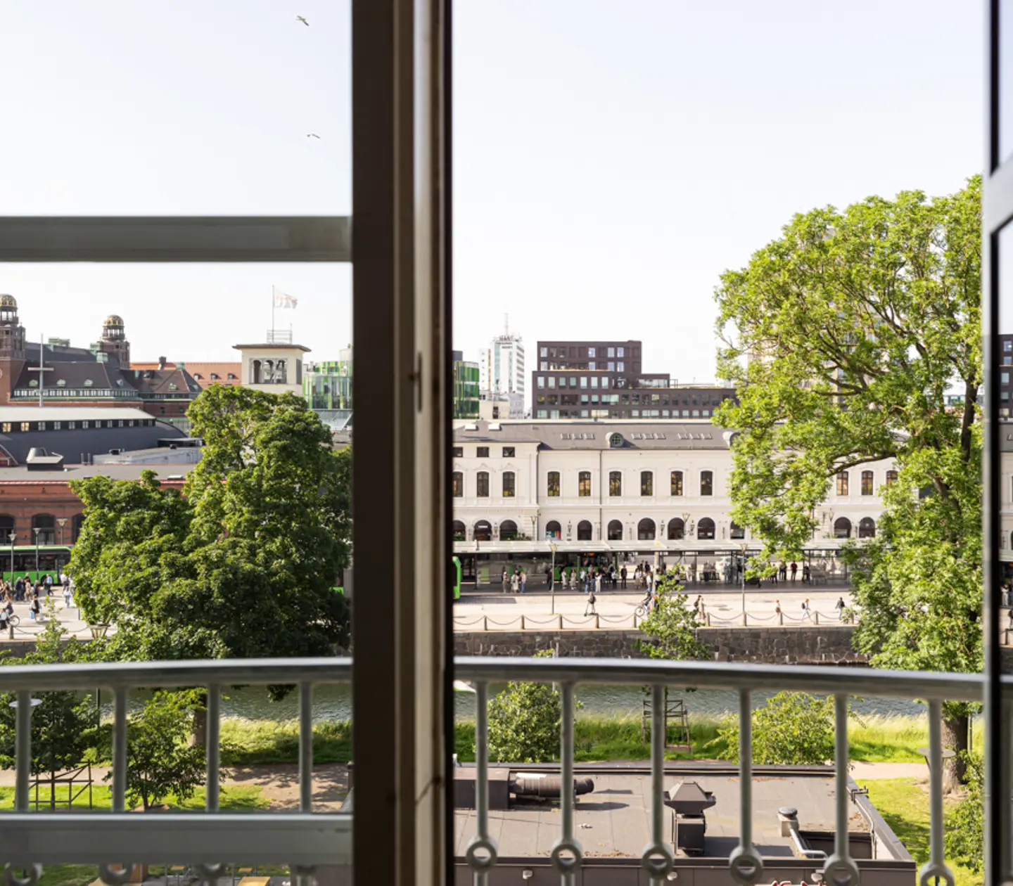 Utsikt från ett fönster över en trädkantad gata och historiska byggnader i centrala Malmö, Sverige.