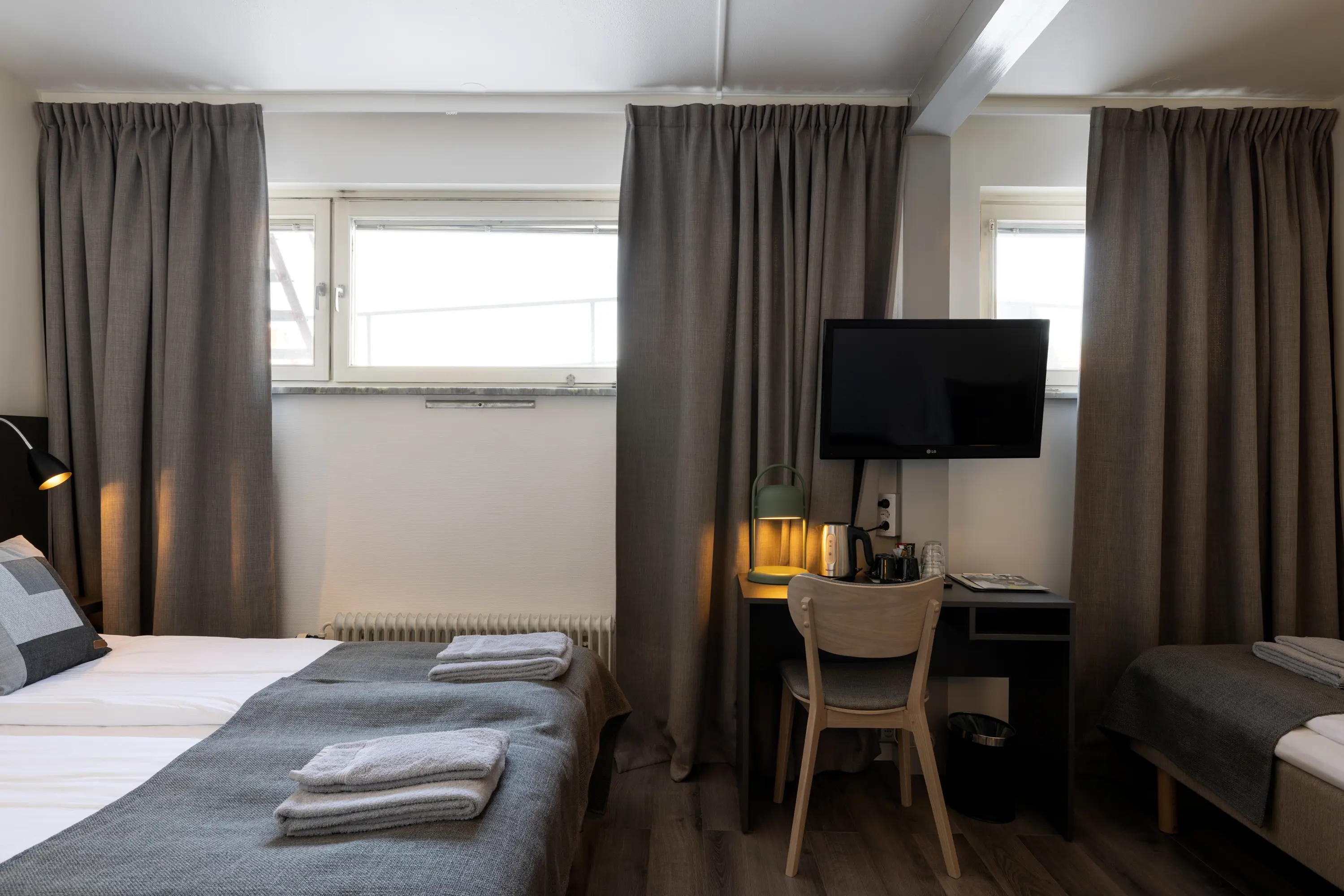 Hotel room with three beds, desk and TV