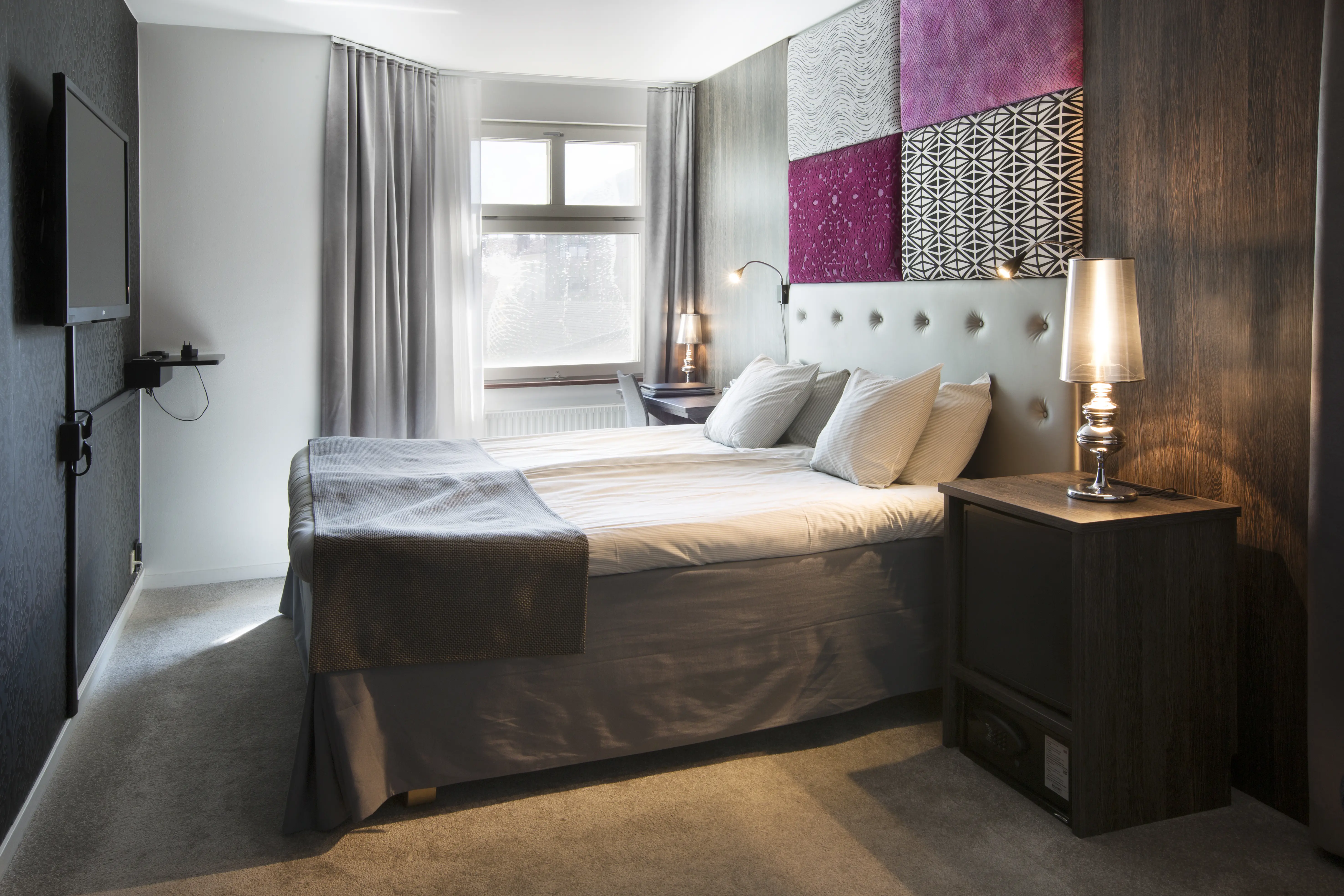 Hotellrum med dubbelsäng, tv och fönster