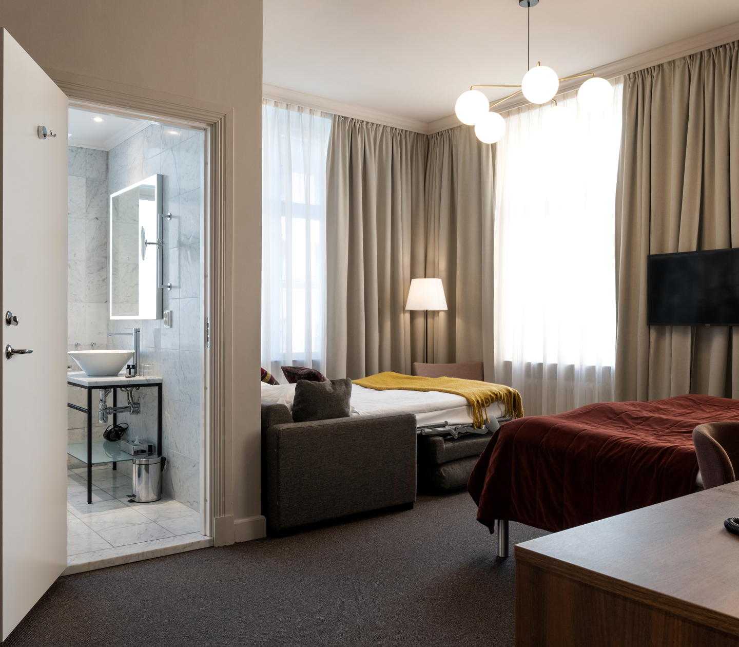 Hotellrum med dubbelsäng, bäddsoffa, badrum och skrivbord