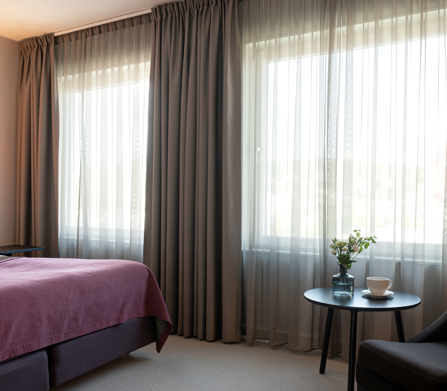 Hotel room with double bed, armchair and large windows