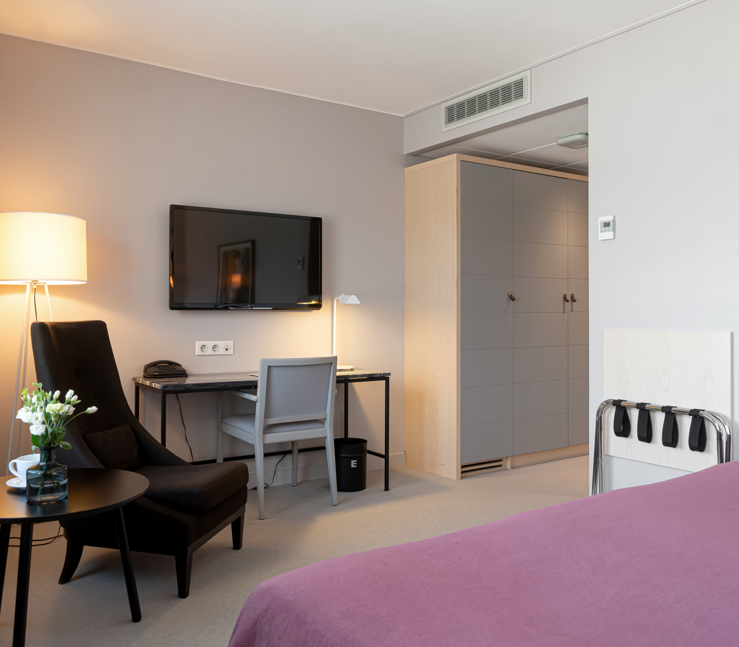 Hotel room with wardrobe, desk and armchair