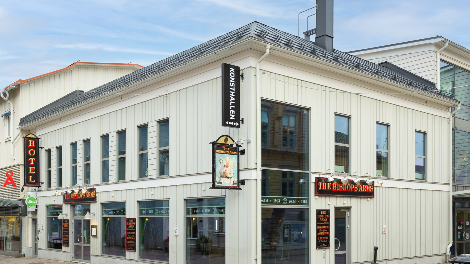 Vita fasaden av Hotel Bishops Arms med skyltar och stora fönster