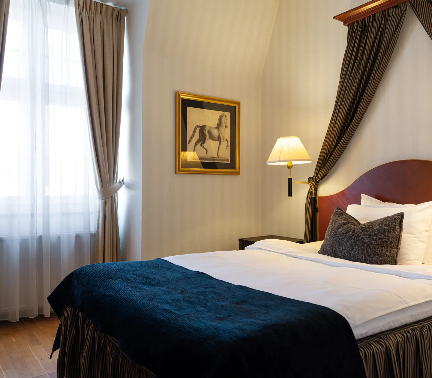 Elegant hotellrum med dubbelsäng, vit sängkläder och blå överkast.