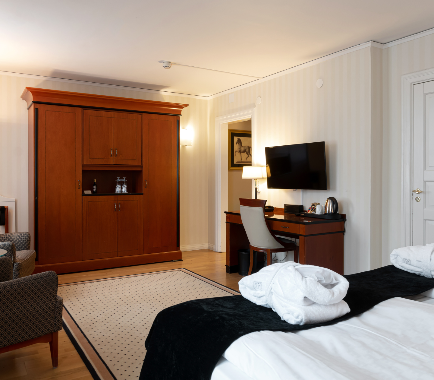 Mysigt hotellrum med morgonrock på säng, garderob och skrivbord