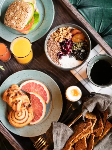 Frukostbricka på grön soffa med frukost, kaffe och juice