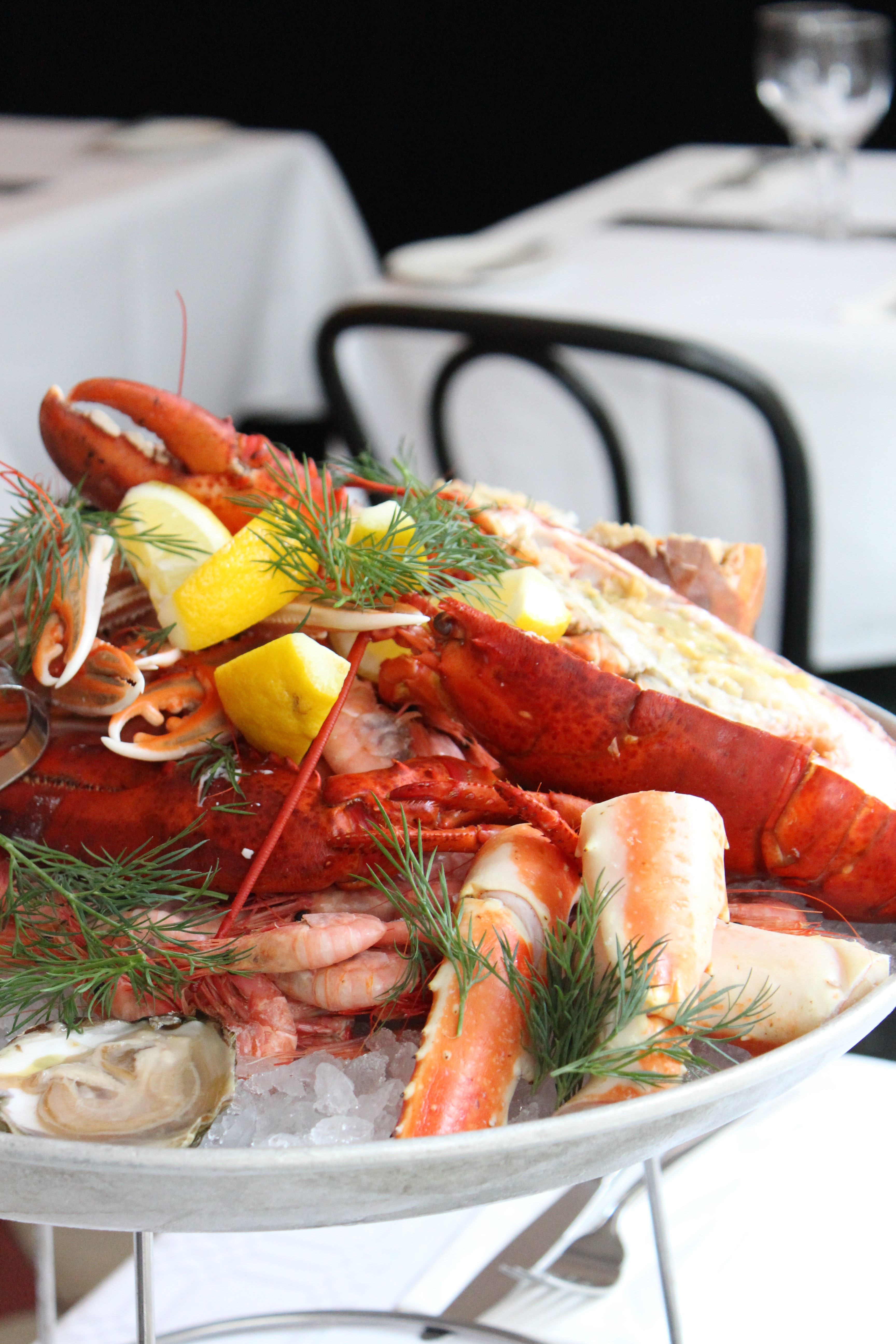 Luxurious seafood platter with lobster, shrimp, oysters, and lemon slices, served on crushed ice and garnished with fresh dill
